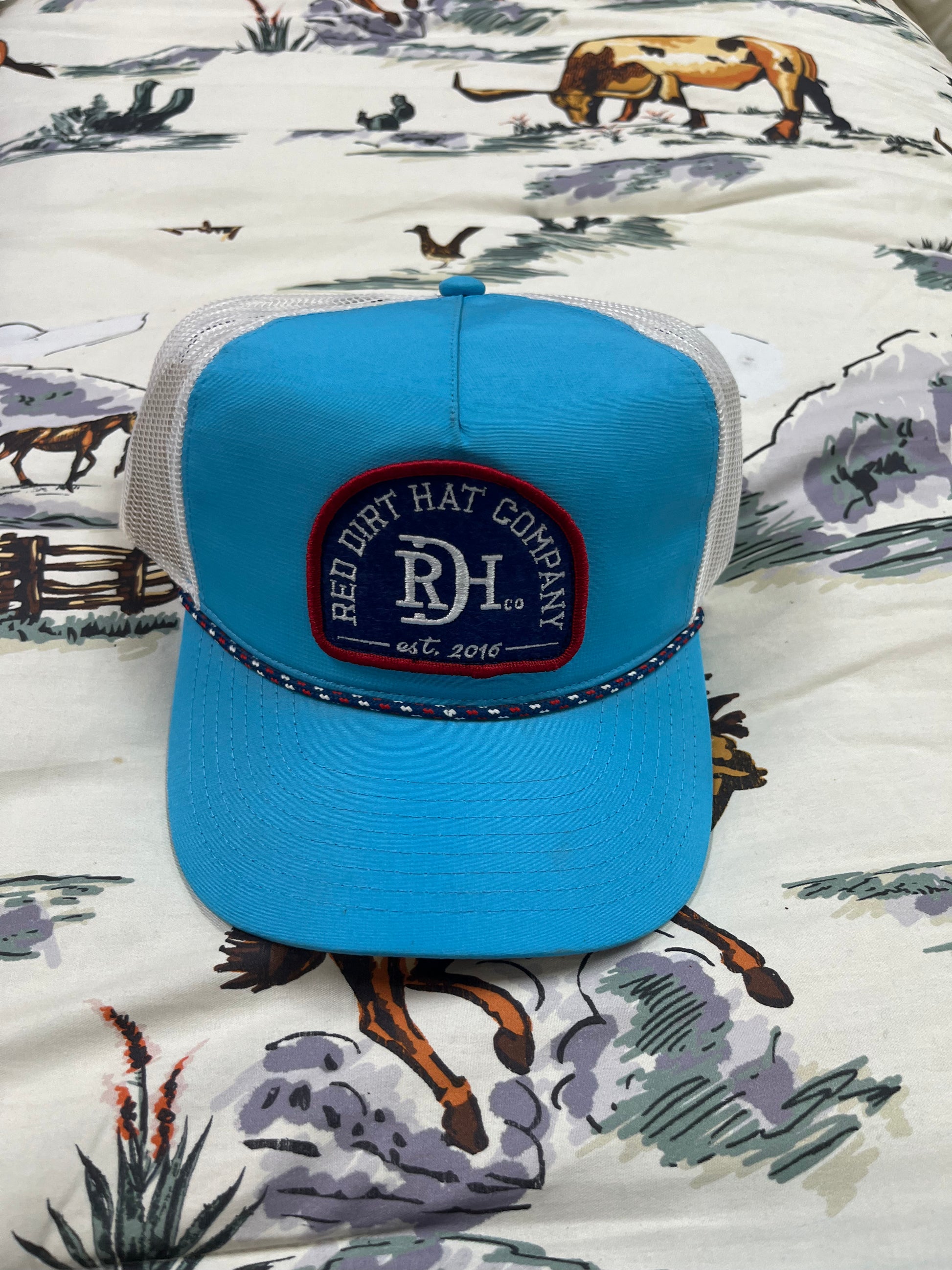 Red Dirt blue patch on a teal/white cap - Wines'Designs